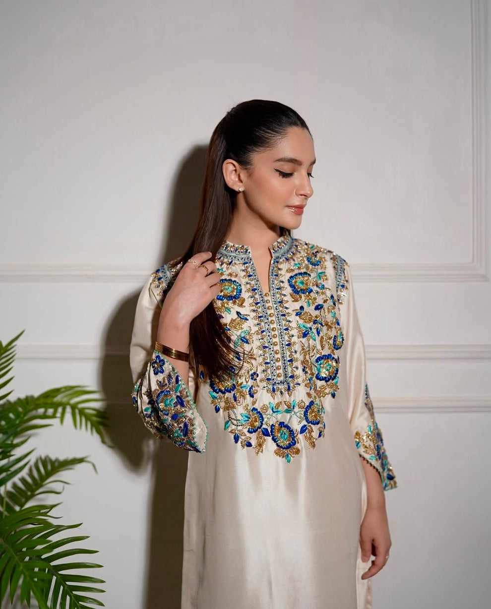 Aleena Khan Aleenah white ensemble featuring a delicately embroidered shirt with intricate motifs, paired with beautifully tailored trousers and a gracefully flowing dupatta, perfect for formal occasions and festive celebrations.