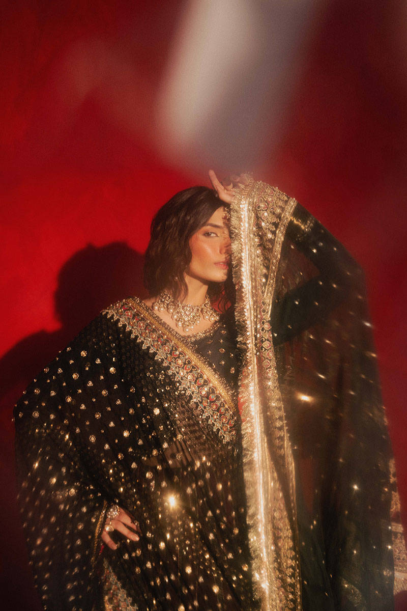 Mohsin Naveed Ranjha Dil Raas black Indian silk lehenga choli featuring a full-sleeved choli with metallic and silk thread embroidery in star-like patterns, paired with a lehenga in deep maroon fading to black with embroidered cypress trees, palmette motifs, mirrorwork, sequins, and golden thread detailing, finished with maroon and gold layered borders, complete with a lightweight organza dupatta featuring maroon and gold floral sprays, gota pati, and adda work, perfect for bridal wear and formal celebratio