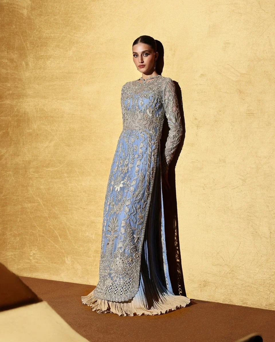 Soraya inspired Seralyn luxury formal ensemble in a soft ethereal pastel palette with subtle warm undertones featuring intricate hand embellishments and shimmering accents on a flowing silhouette with a richly worked bodice and embellished flare, paired with a coordinated dupatta with elegant borders, perfect for weddings and formal celebrations.