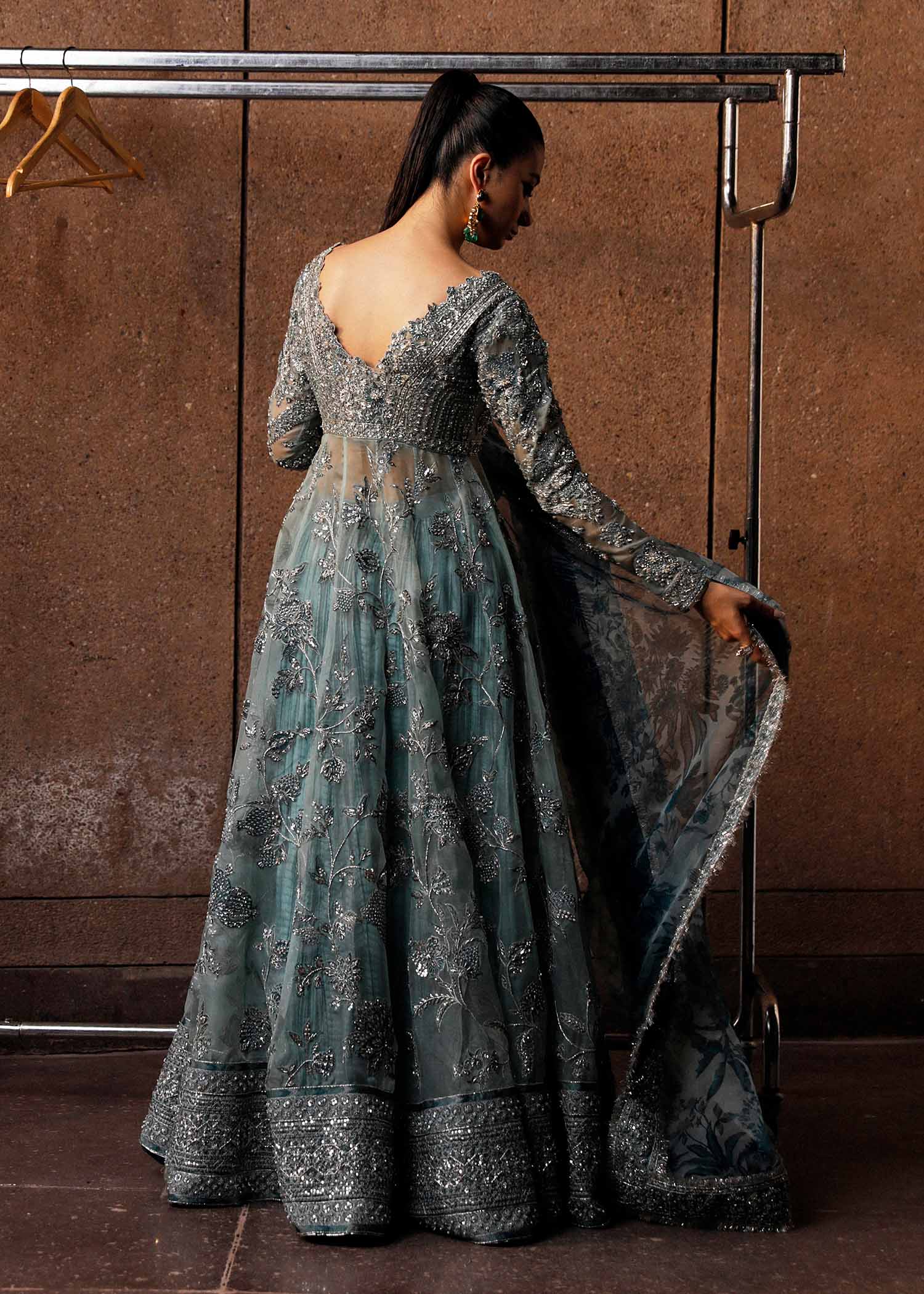 Hussain Rehar Astra ice-blue organza peshwas featuring intricate embellishments on the front and back bodice with heavy embellished borders, paired with a resplendent silk crushed sharara and a digital printed organza dupatta with celestial motifs and four-sided embellished border, perfect for weddings and formal celebrations.

