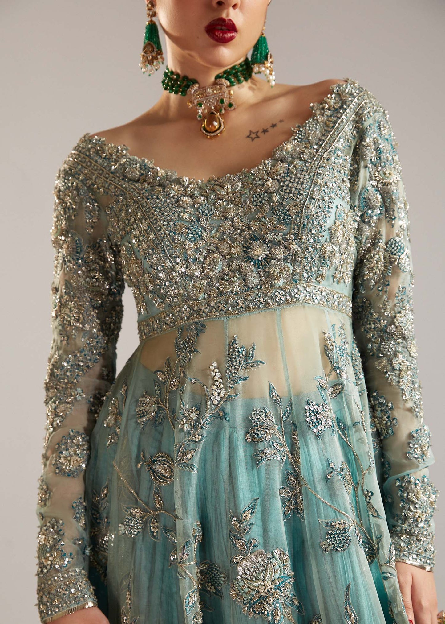  Hussain Rehar Astra ice-blue organza peshwas featuring intricate embellishments on the front and back bodice with heavy embellished borders, paired with a resplendent silk crushed sharara and a digital printed organza dupatta with celestial motifs and four-sided embellished border, perfect for weddings and formal celebrations.
