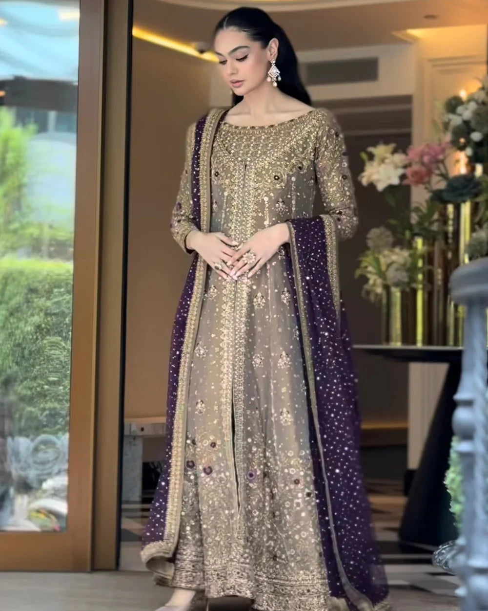 Haris Shakeel Aroha brushed bronze wedding ensemble featuring a luminous antique gold and soft champagne formal outfit with intricate hand embellishments and detailed embroidery, paired with a rich deep purple dupatta for a regal contrast, perfect for weddings, receptions, engagements, and formal celebrations.