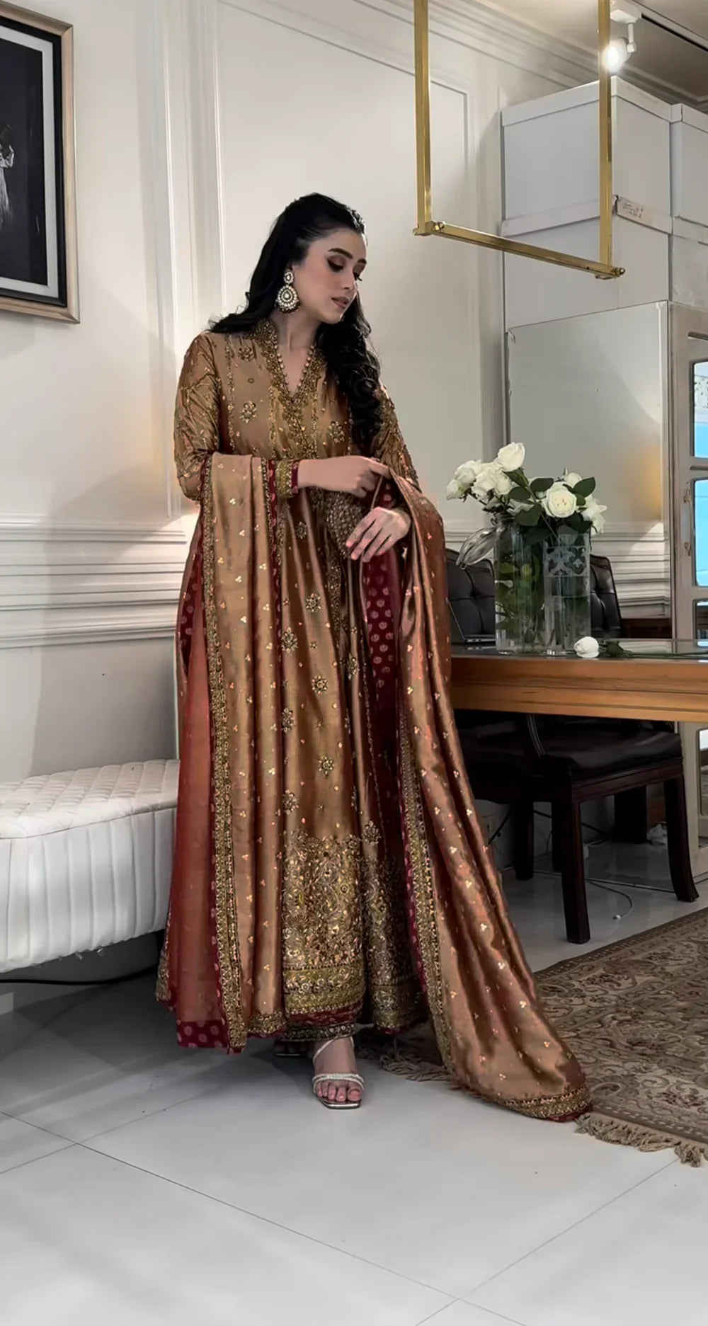 Haris Shakeel Aswad bronze-gold formal ensemble featuring intricate hand embellishments with detailed floral motifs, delicate sequins, and refined accents on an elongated silhouette with a heavily worked hemline, perfect for weddings, receptions, formal dinners, and festive celebrations.