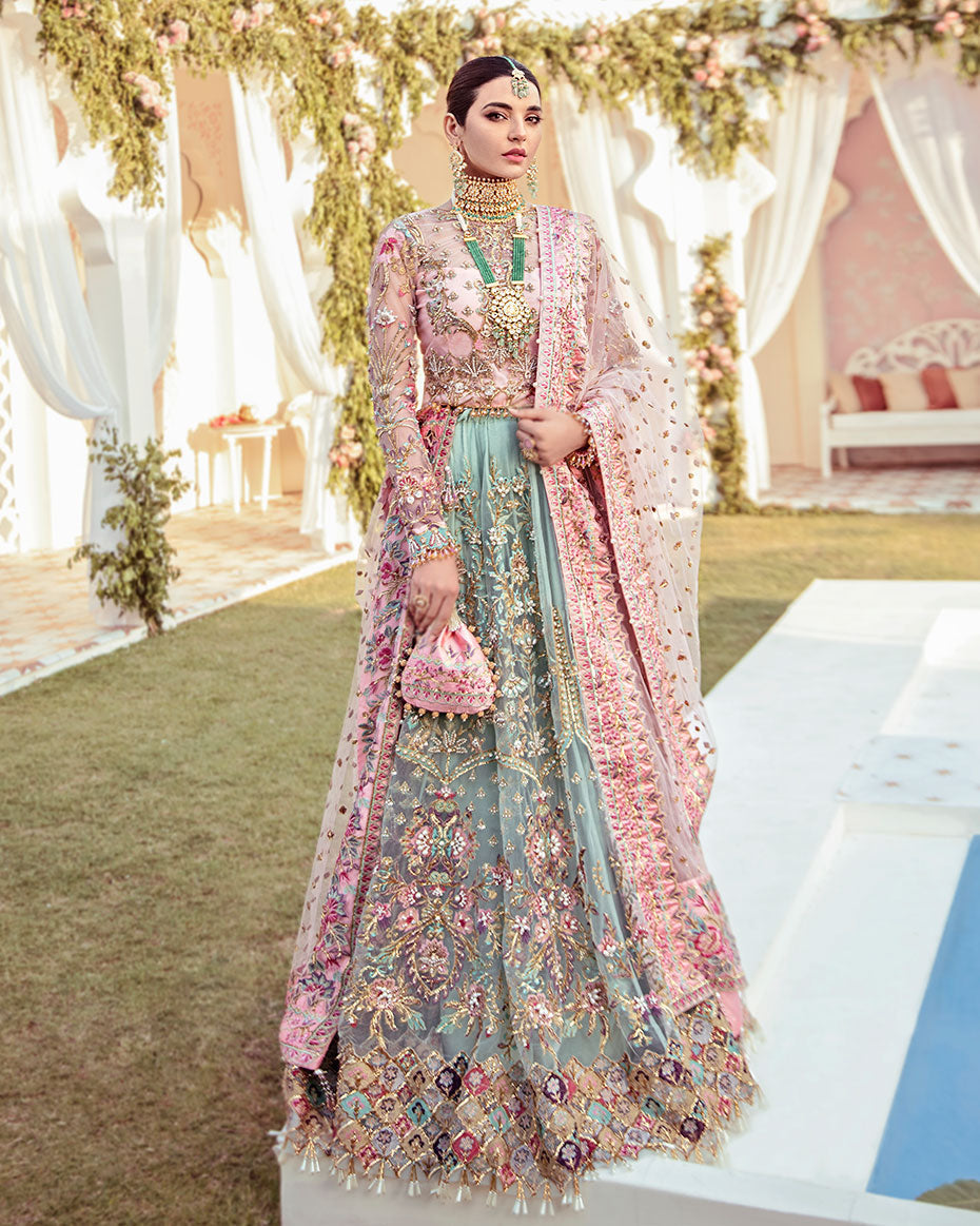 Joli Rajkumari lehenga choli in a unique color block of pink and sea green featuring intricately hand-worked embellishments with pearls, gotta, dabka, nakshi, crystals, mukaish, and pitta, paired with a pink tulle dupatta filled with booti spray and four-sided silk borders with heavy pearl tassel details, inspired by Rajasthani culture.