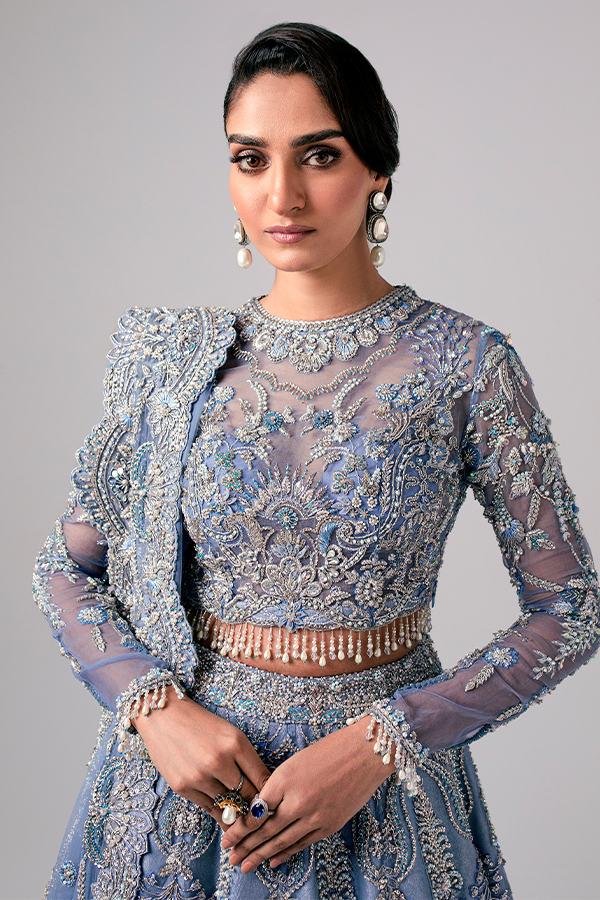 The Nyra Couture Aarzu sky blue net lehenga choli featuring heavy florid embroidery with resham thread, naqshi, dabka, sequin, and pearls, paired with a heavy net dupatta, perfect for wedding celebrations and bridal events.