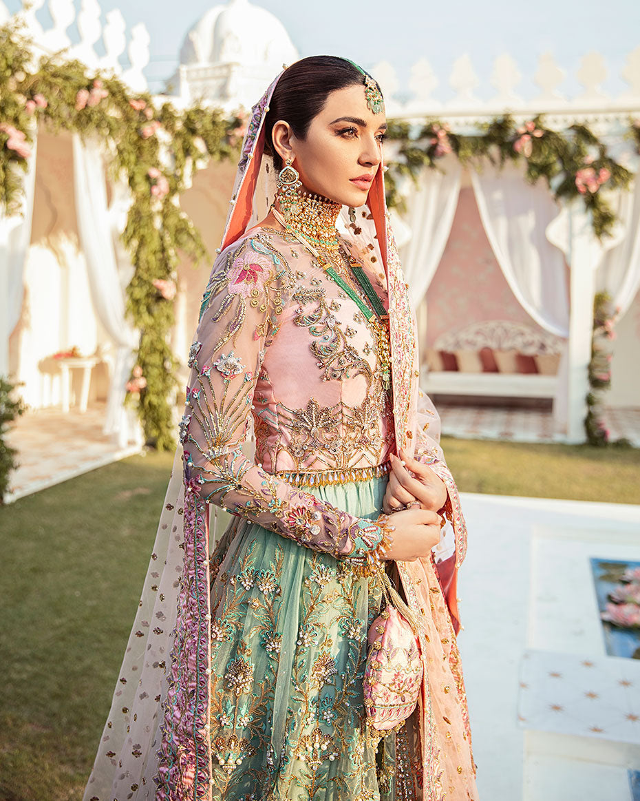 Joli Rajkumari lehenga choli in a unique color block of pink and sea green featuring intricately hand-worked embellishments with pearls, gotta, dabka, nakshi, crystals, mukaish, and pitta, paired with a pink tulle dupatta filled with booti spray and four-sided silk borders with heavy pearl tassel details, inspired by Rajasthani culture.