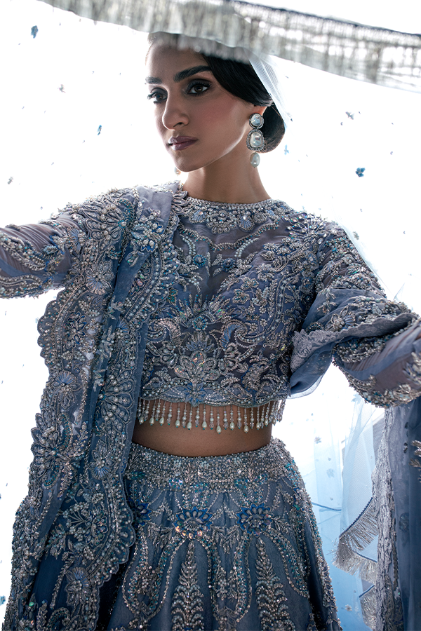 The Nyra Couture Aarzu sky blue net lehenga choli featuring heavy florid embroidery with resham thread, naqshi, dabka, sequin, and pearls, paired with a heavy net dupatta, perfect for wedding celebrations and bridal events.