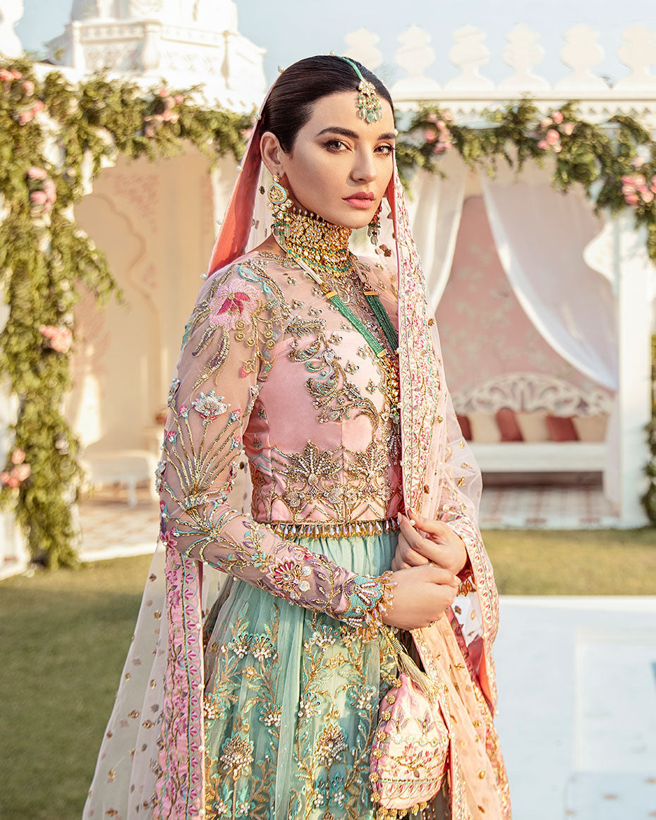 Joli Rajkumari lehenga choli in a unique color block of pink and sea green featuring intricately hand-worked embellishments with pearls, gotta, dabka, nakshi, crystals, mukaish, and pitta, paired with a pink tulle dupatta filled with booti spray and four-sided silk borders with heavy pearl tassel details, inspired by Rajasthani culture.